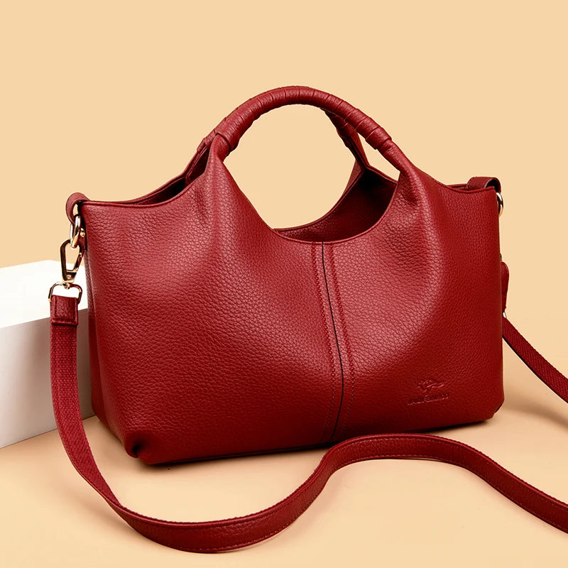 Red leather handbag with a strap on a beige background