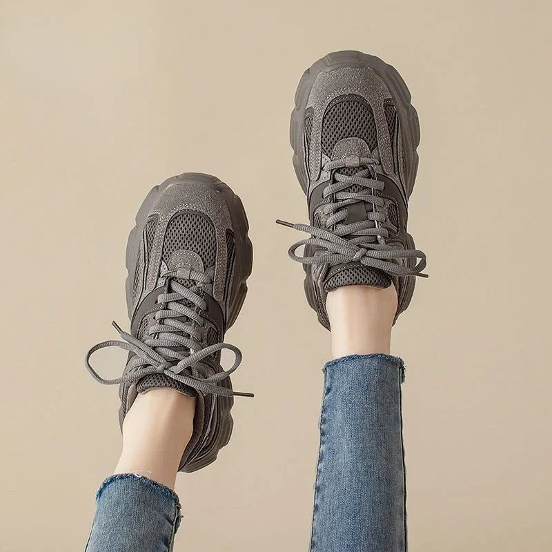 Gray sneakers worn with blue jeans against a beige background