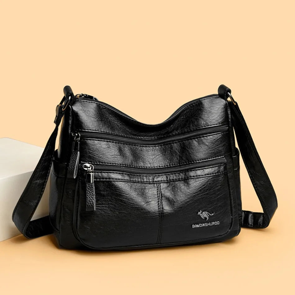 Black leather handbag with multiple pockets and a visible brand logo on a beige background
