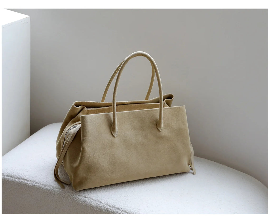 Beige handbag on a white surface with a neutral background