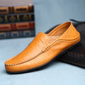 Orange leather loafer shoe on a light blue surface with books in the background