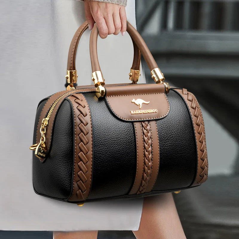 Black and brown handbag with gold accents held by a person, featuring a visible brand logo.