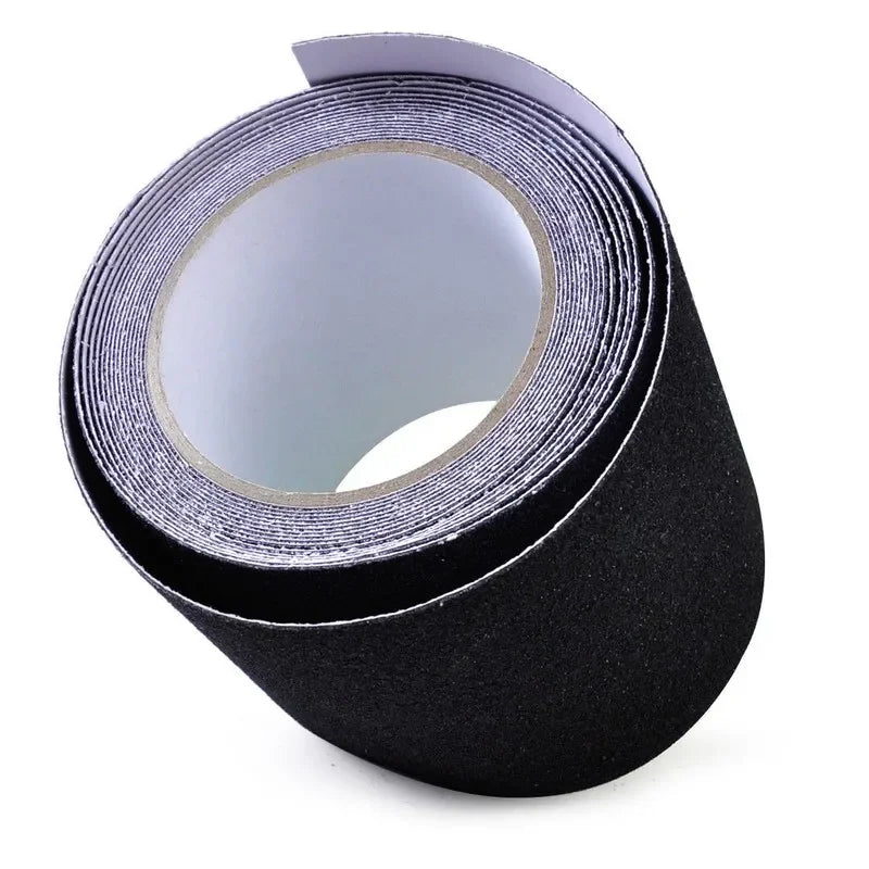 A roll of black adhesive tape with a textured surface, partially unrolled to show its light gray backing, set against a plain white background.