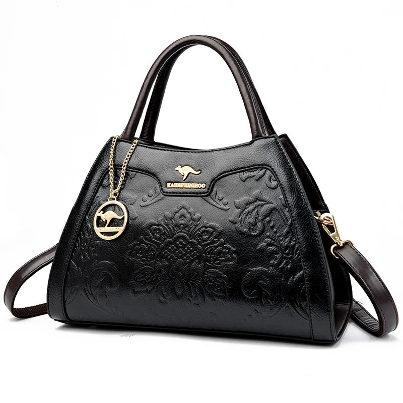 Black handbag with floral embossing and a gold chain on a white background