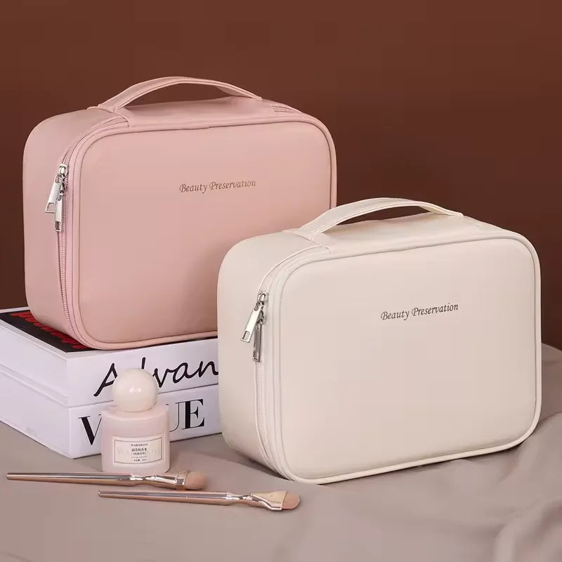 Two cosmetic bags, one pink and one beige, with a small bottle and brushes on a brown surface.