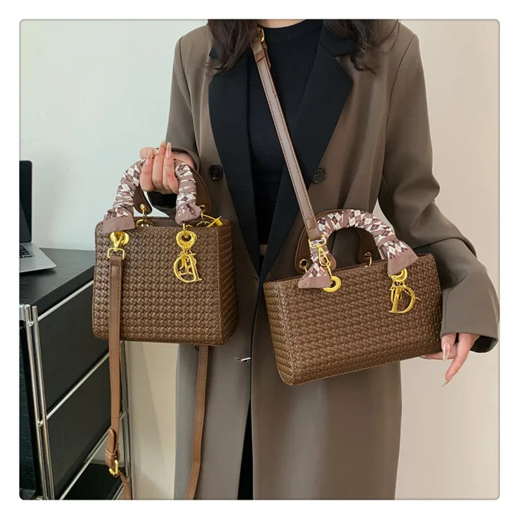 Person holding two brown handbags with gold hardware in an office setting