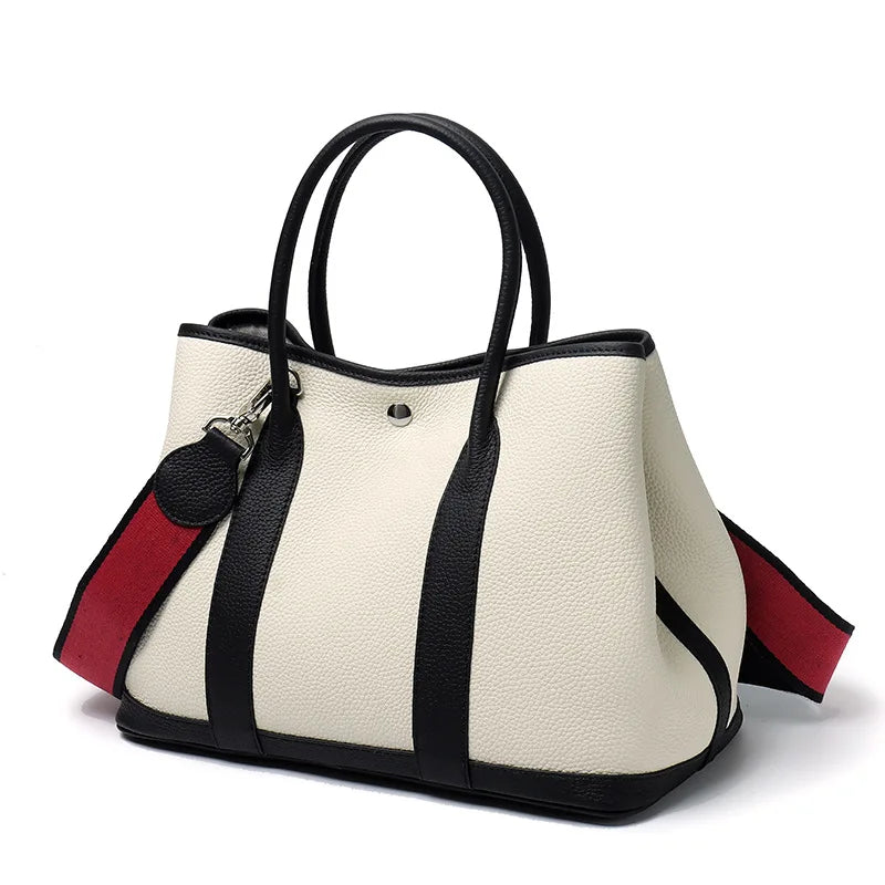 White handbag with black and red accents on a white background
