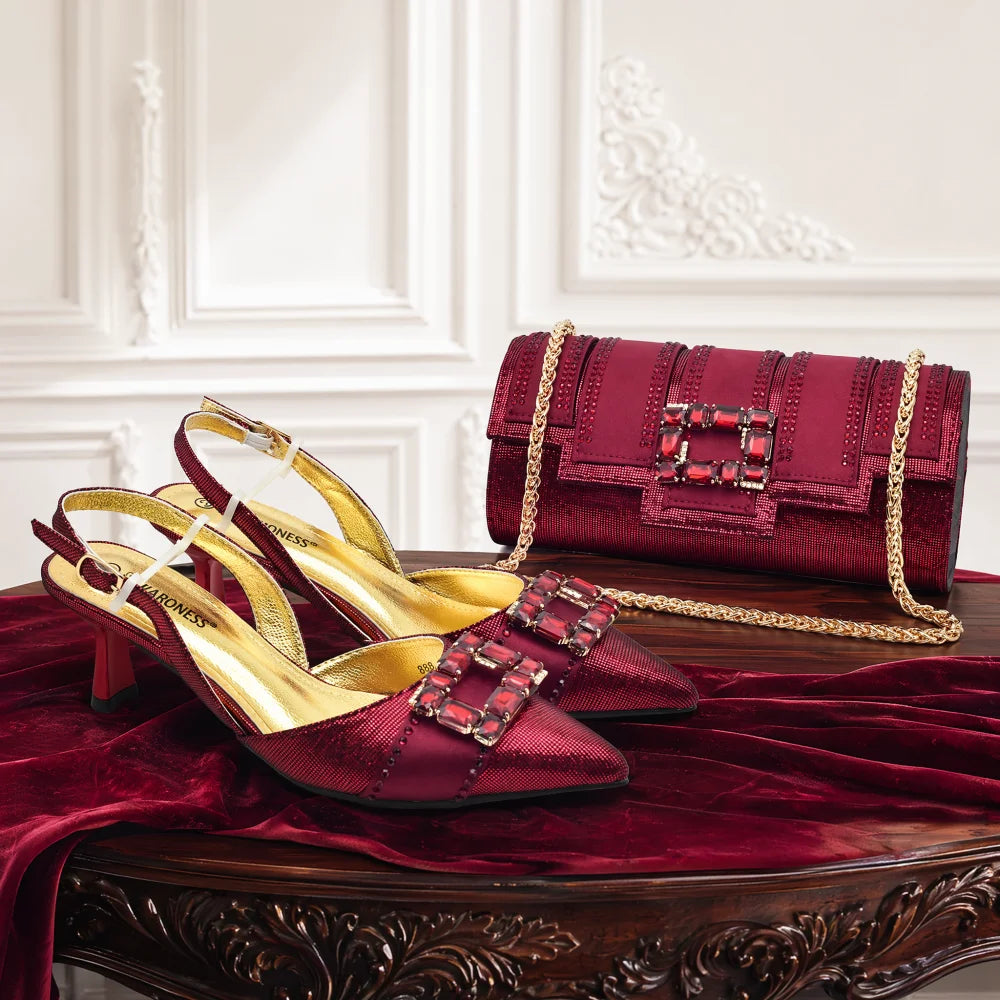 A matching burgundy and gold luxury handbag set, including a structured shoulder bag with a gold chain strap and a pair of pointed-toe slingback heels, displayed on a dark wood table draped with burgundy velvet.
