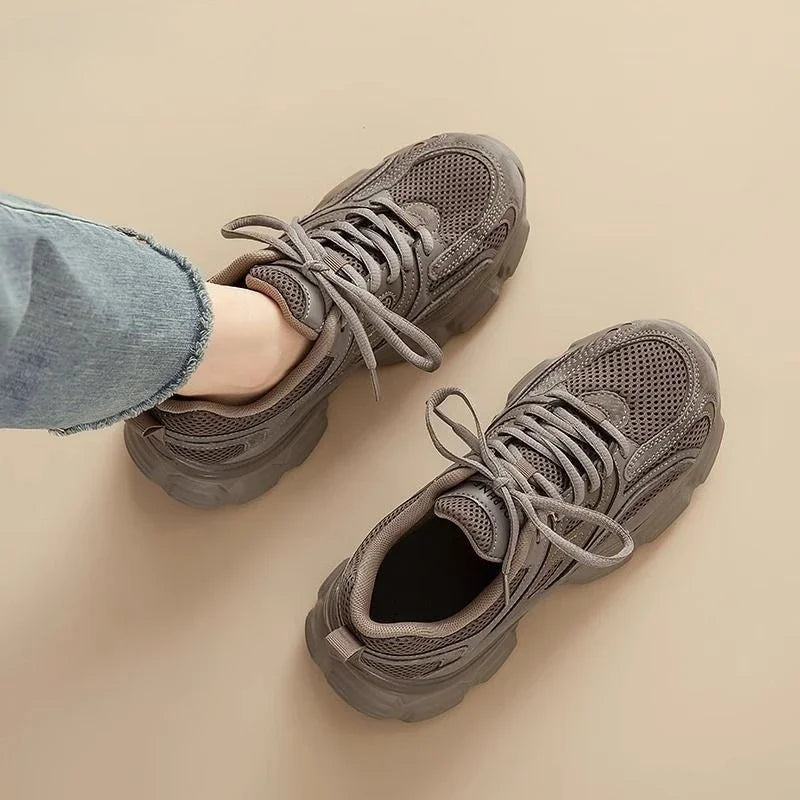 Gray sneakers worn with jeans on a beige background