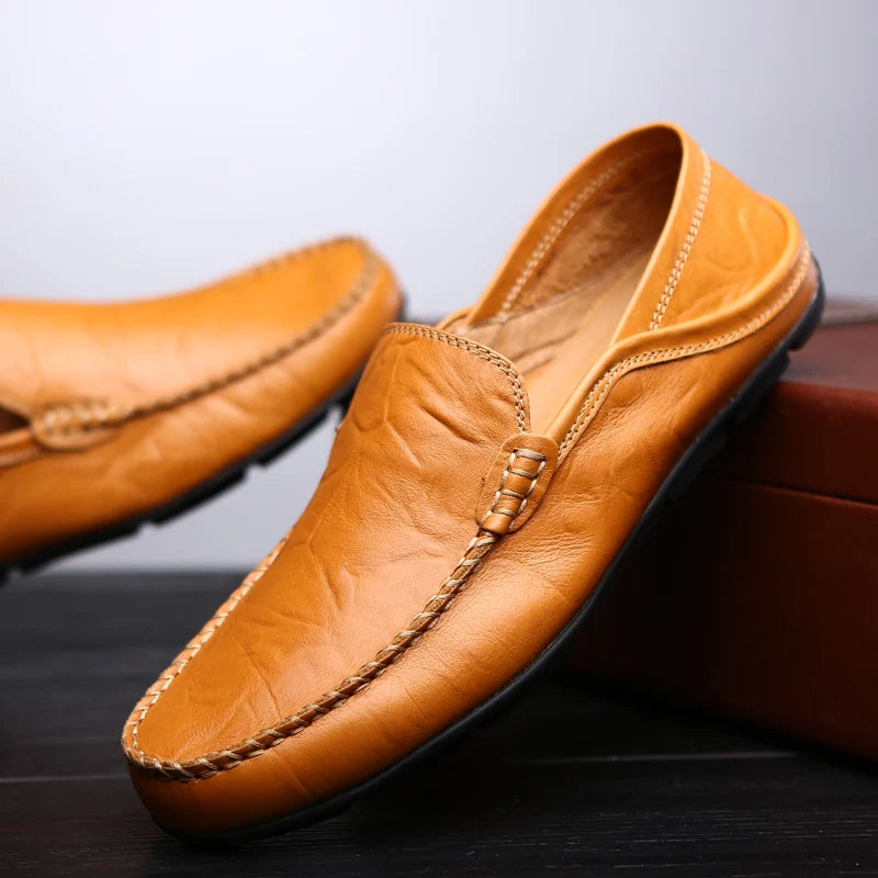 Brown leather loafers on a dark surface with a light gray background
