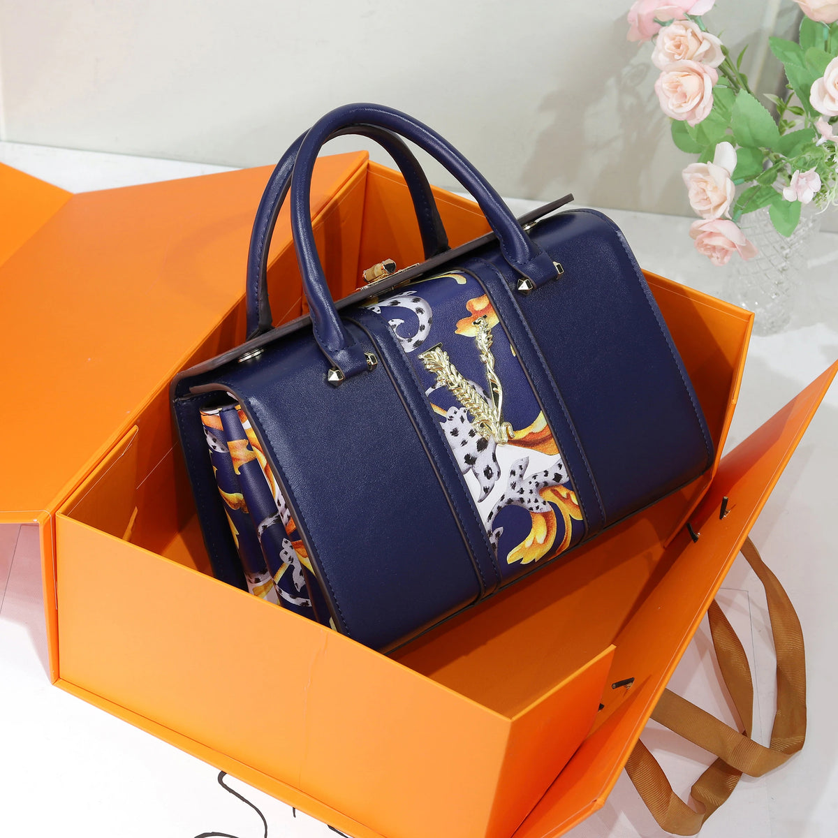 Navy blue handbag with floral pattern in an orange box