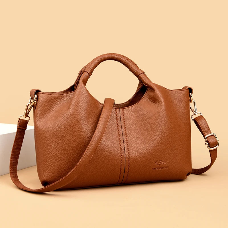 Brown leather handbag with a strap on a beige background