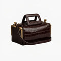 Brown crocodile-patterned handbag with gold accents on a white background