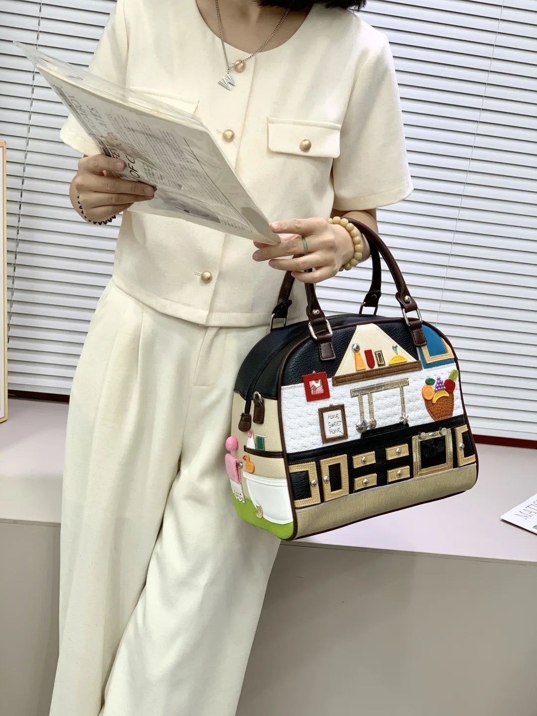 Person holding a patterned handbag with a building design in an indoor setting