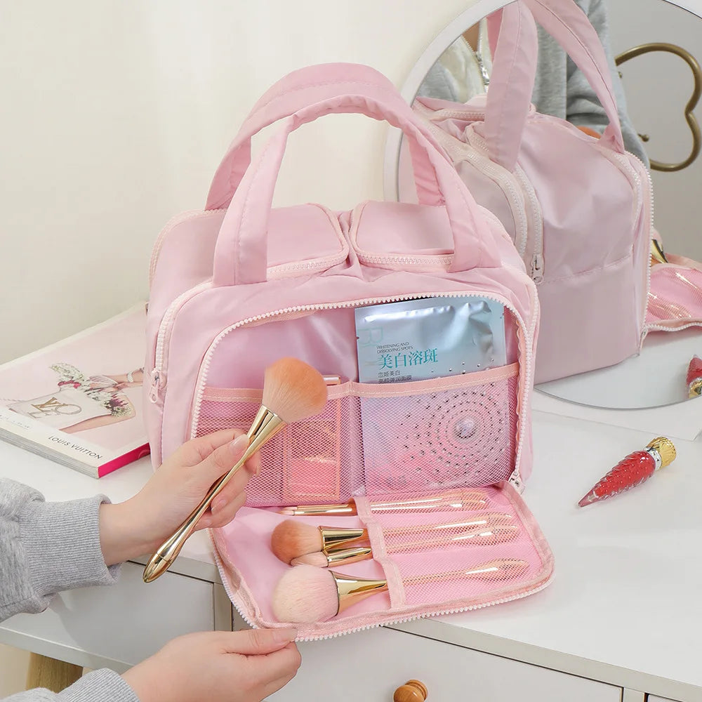 Pink makeup bag with brushes and products on a white surface