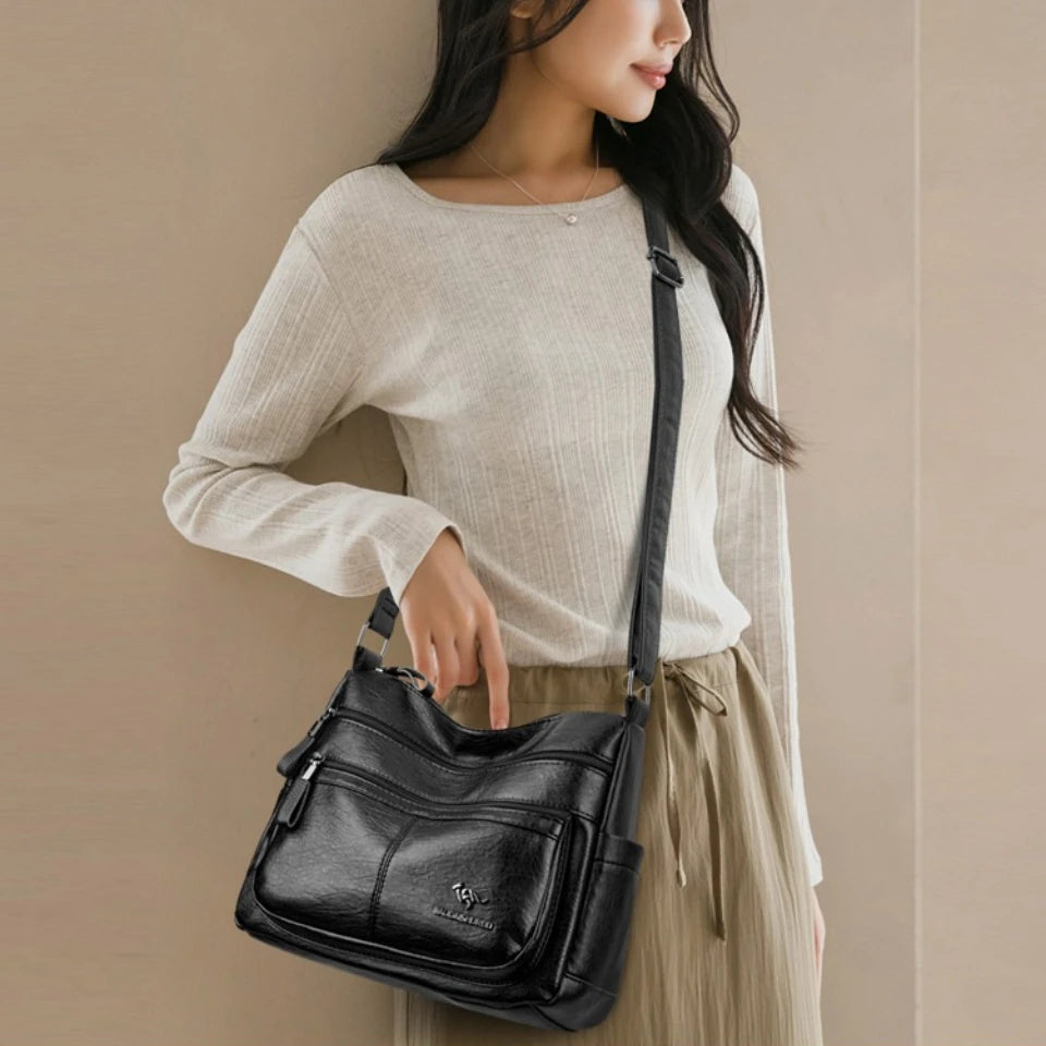 Woman holding a black handbag against a beige background