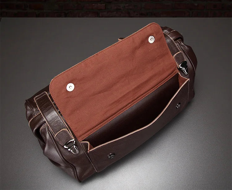 Brown leather bag with open flap on a gray background