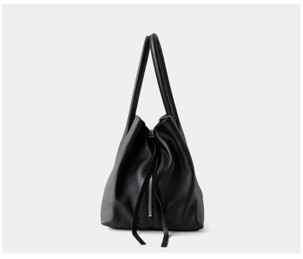 Black handbag with a drawstring on a light gray background