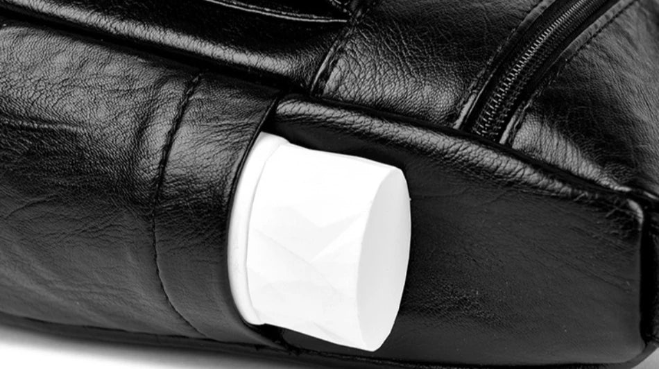 Close-up of a black leather bag with a white cylindrical object inside