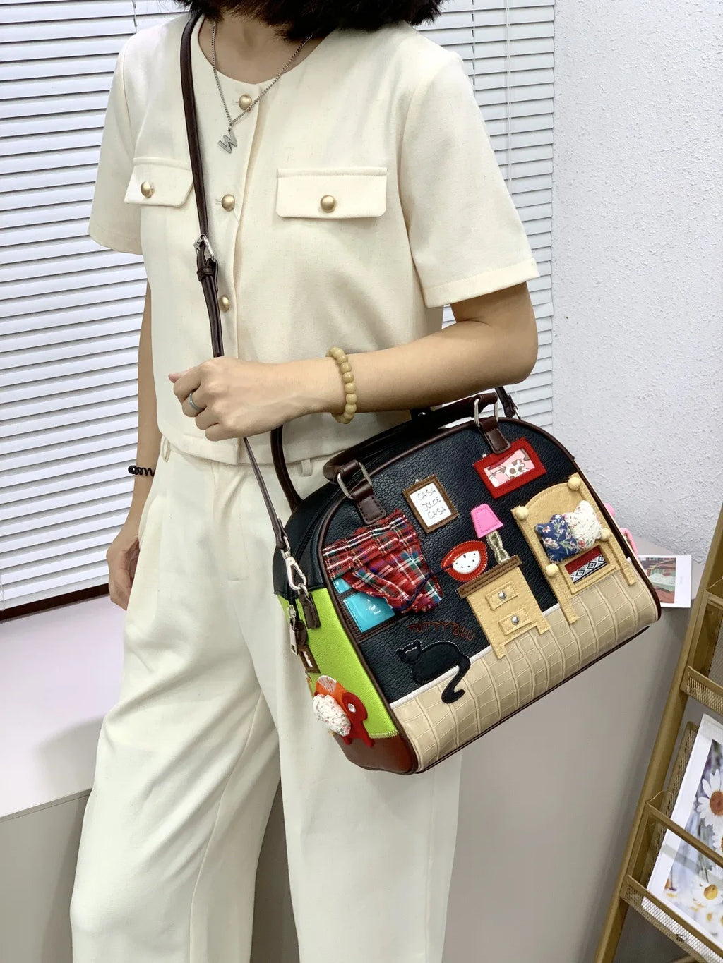 Person holding a decorative handbag with various small images and designs on it.