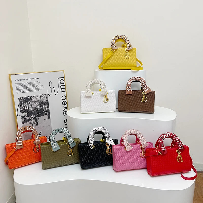 Collection of colorful handbags displayed on a white surface with a magazine in the background.