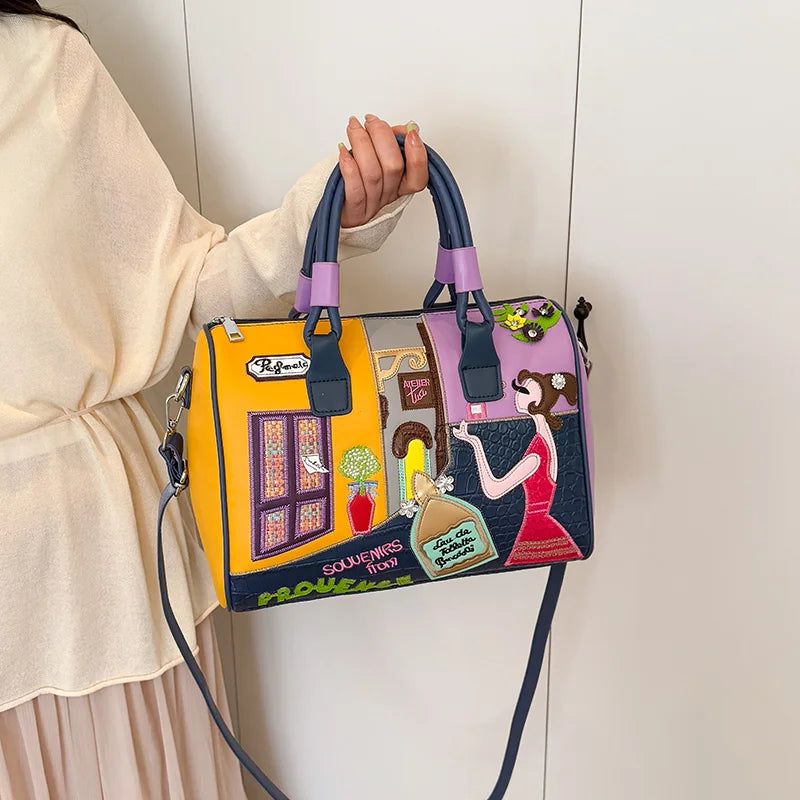 Colorful handbag with artistic design held by a person against a plain background