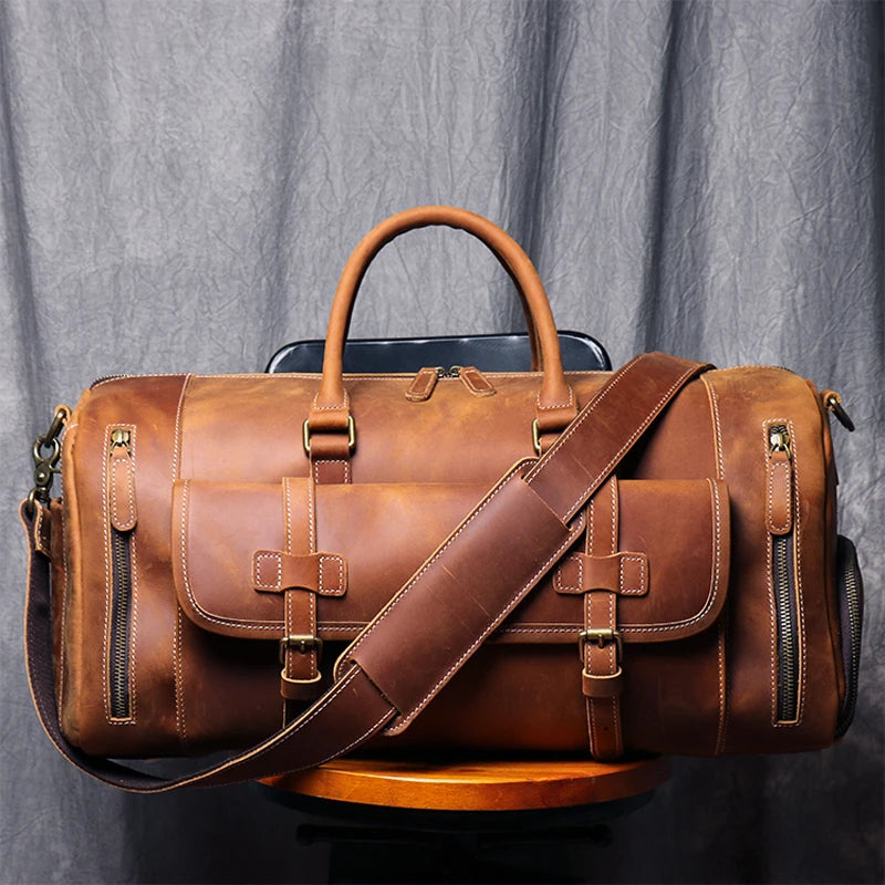 Brown leather duffel bag with shoulder strap on a gray background