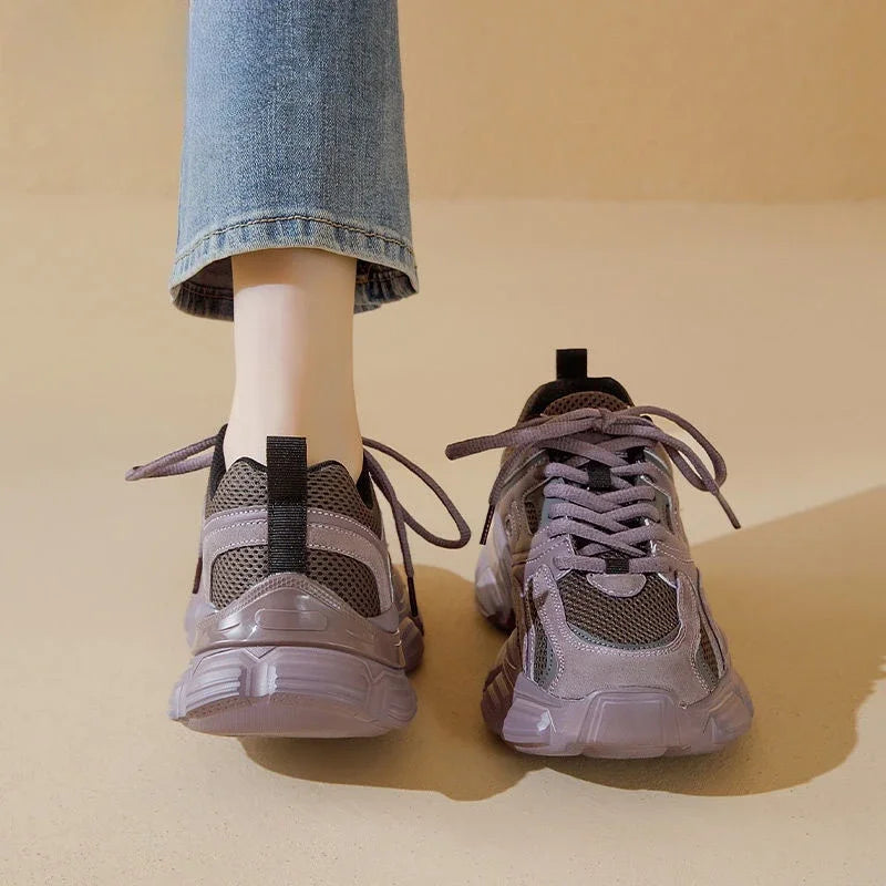 Gray sneakers worn with blue jeans on a beige background