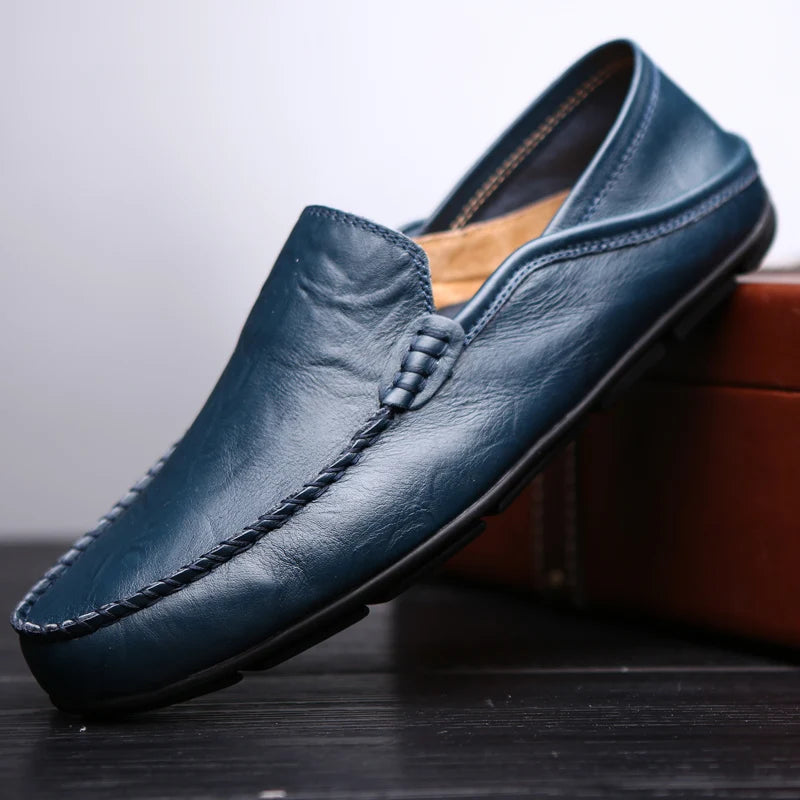Blue leather loafer shoe on a dark surface with a blurred background