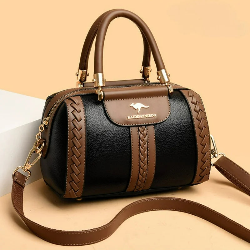 A black and brown leather handbag with braided side details, dual top handles, a front flap with a kangaroo logo and 'BAOMAOBAO' text, and a detachable shoulder strap, shown on a beige background.