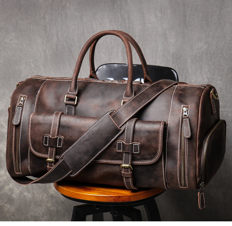 Brown leather duffel bag with shoulder strap on a gray background