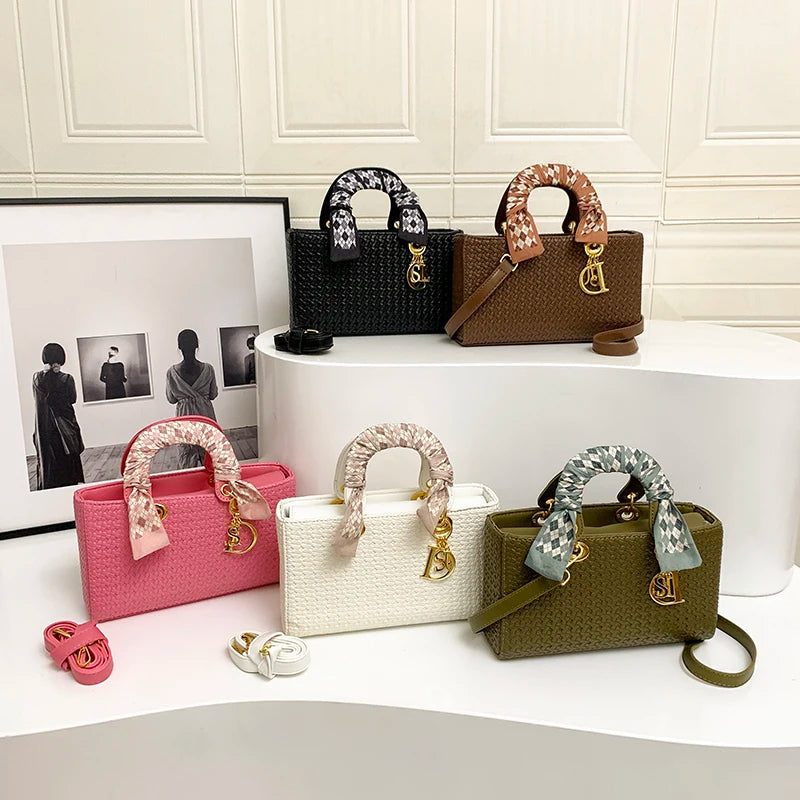 Collection of handbags in various colors on a white surface with a framed photo in the background.
