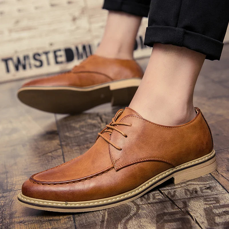 Brown leather shoes worn by a person on a textured floor.
