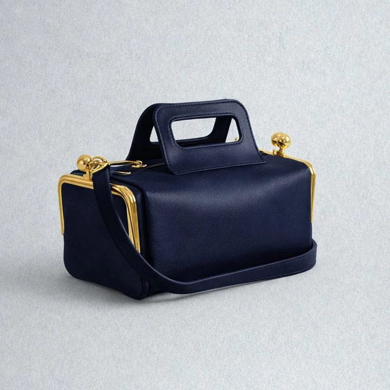 Navy blue handbag with gold accents on a light gray background