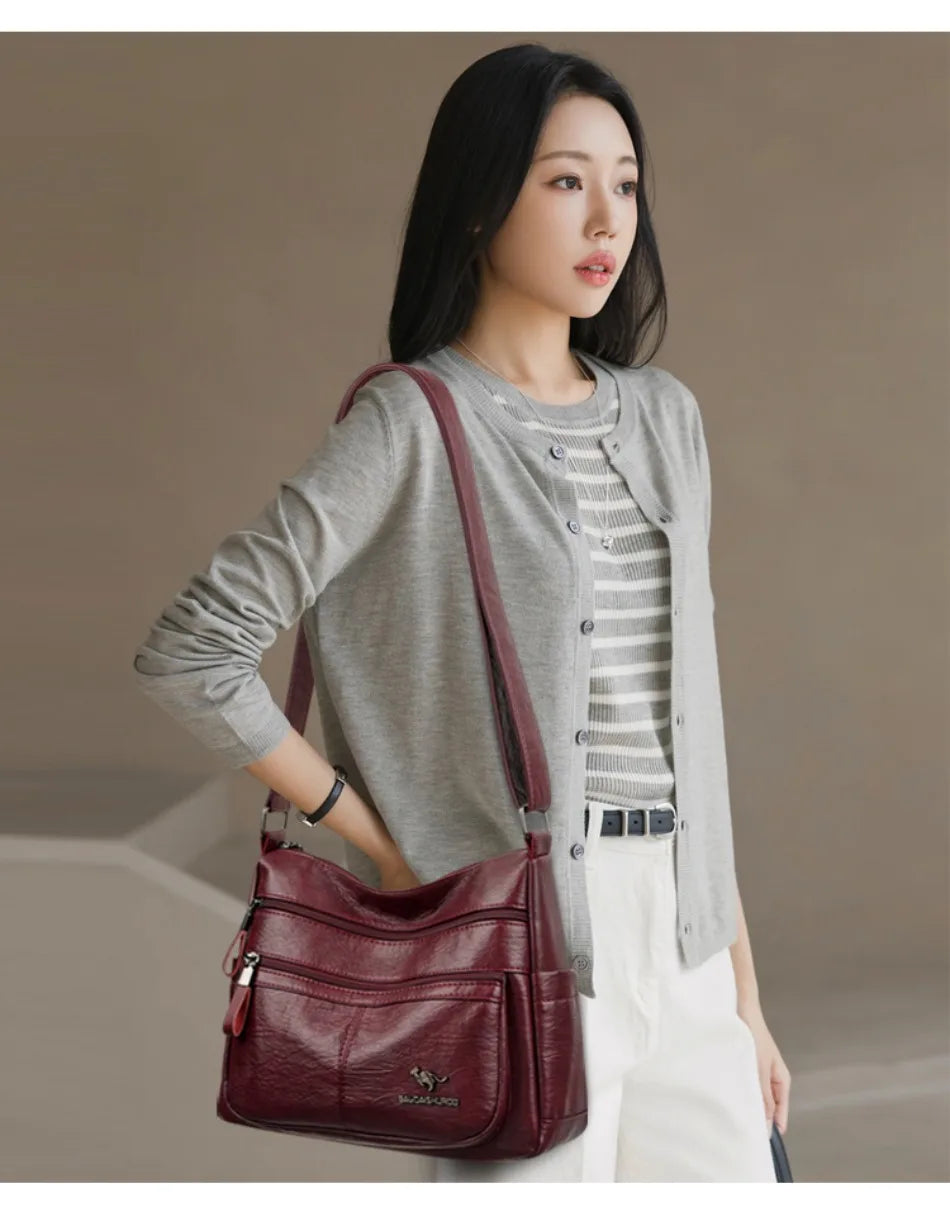 Woman holding a maroon handbag against a neutral background