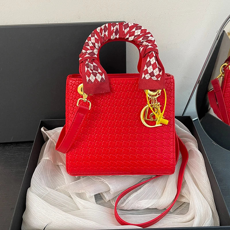 Red handbag with a decorative handle on a white fabric background