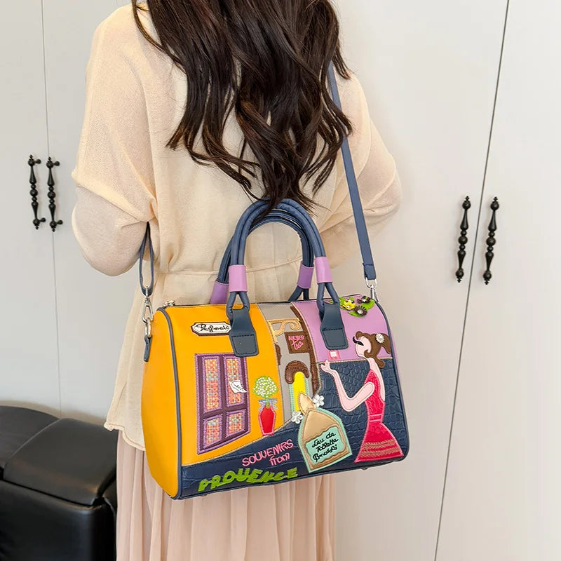 Colorful handbag with artistic design held by a person against a neutral background