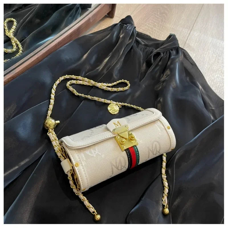 Beige handbag with gold chain strap on black fabric background