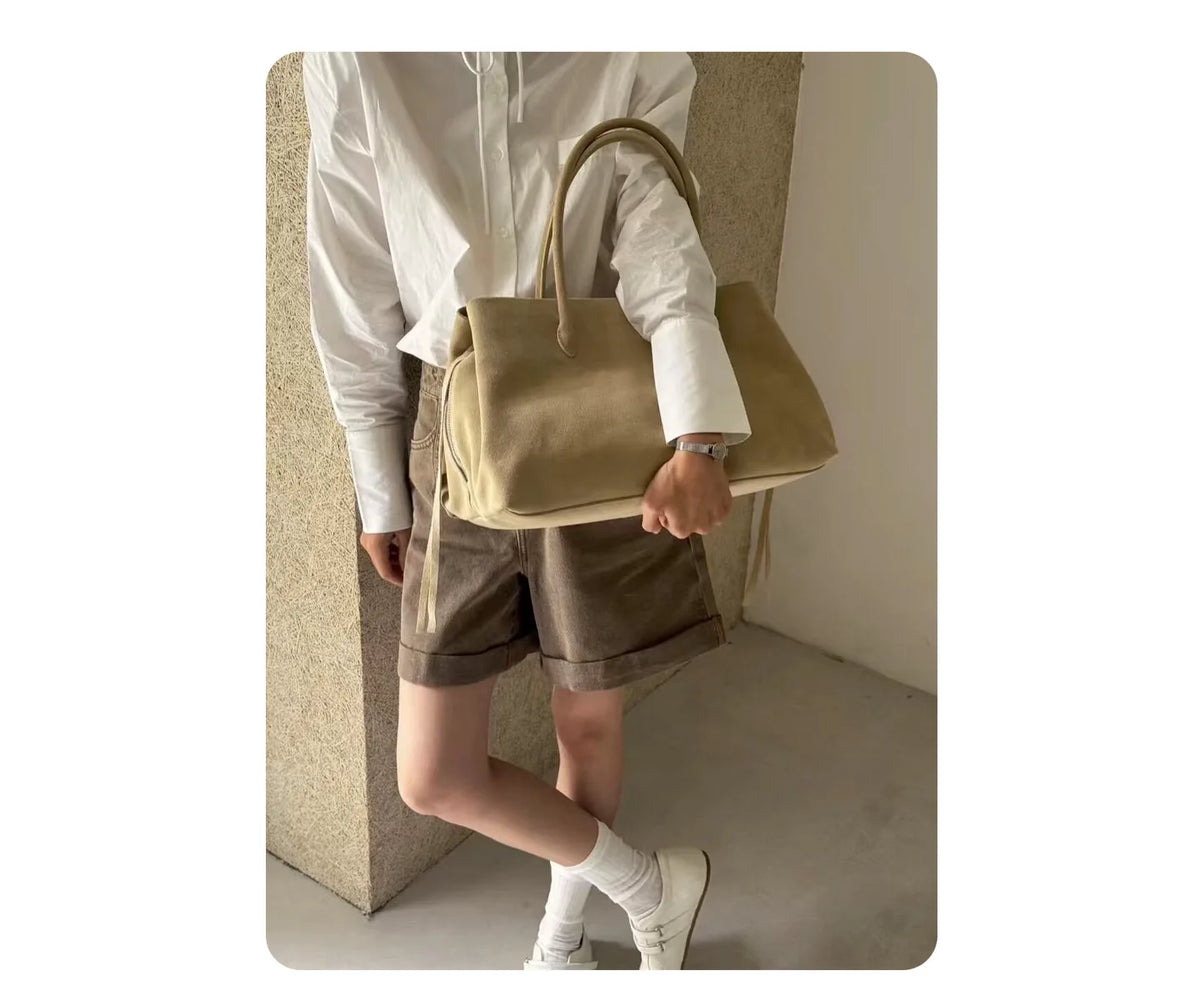 Person holding a beige handbag in a minimalistic setting