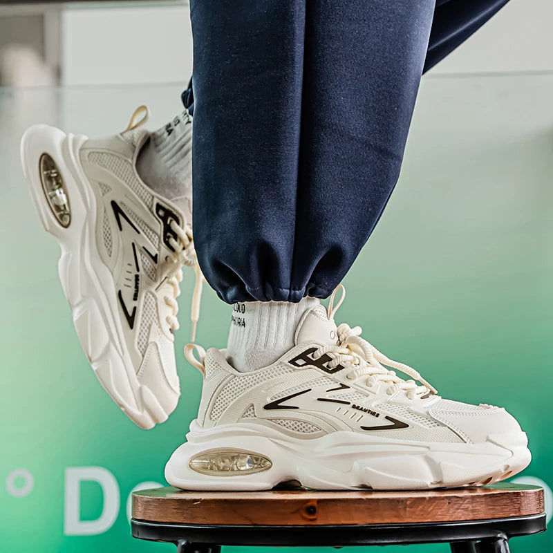 White sneakers with black accents worn by a person on a stool against a blurred background