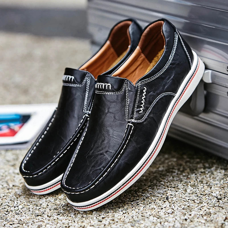 Black leather shoes with white stitching on a textured surface