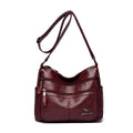 Maroon handbag with a strap on a white background
