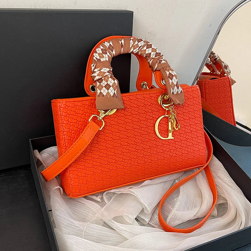 Orange handbag with a checkered strap in a box