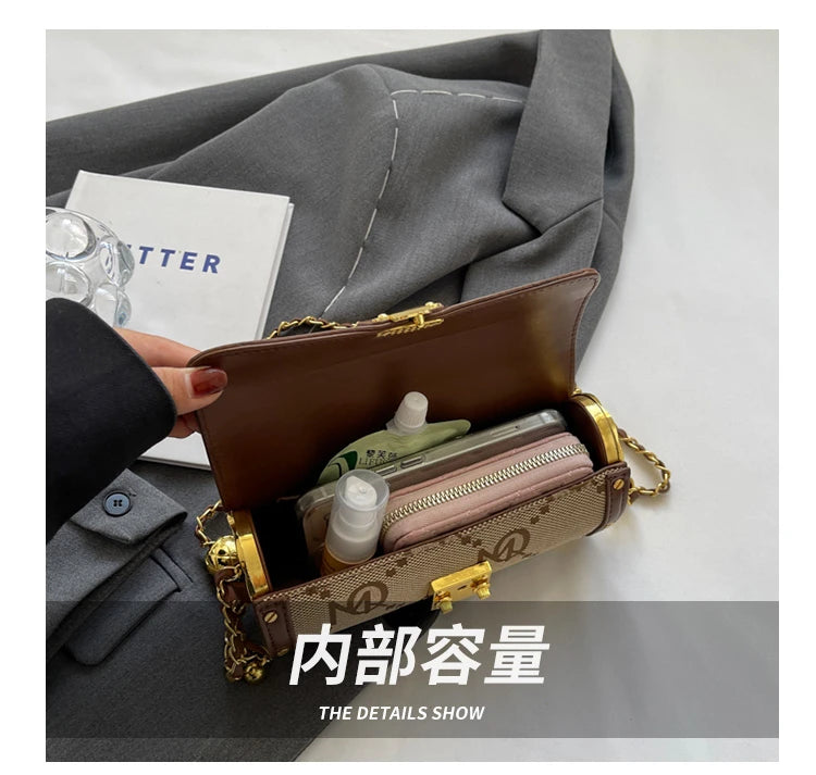 Brown handbag with gold accents open on a gray surface, showing its contents.