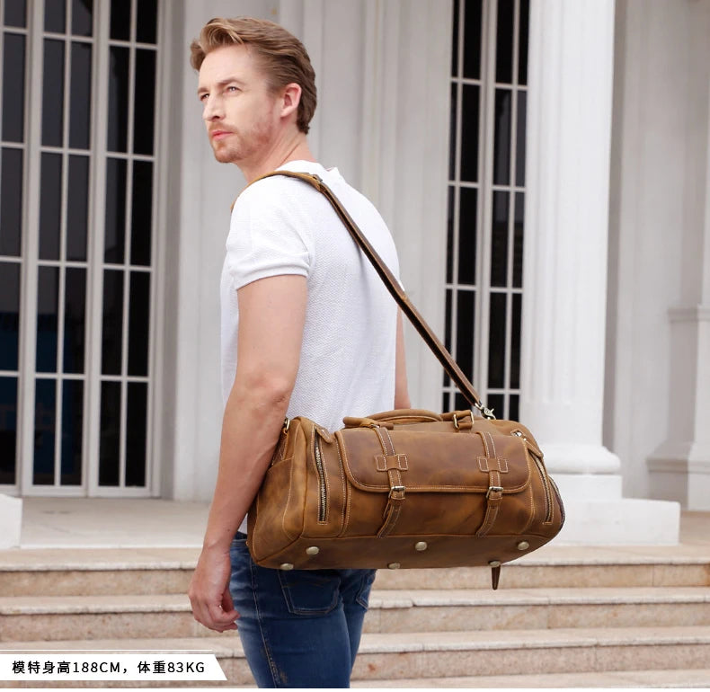 Man carrying a brown leather duffel bag in front of classical architecture