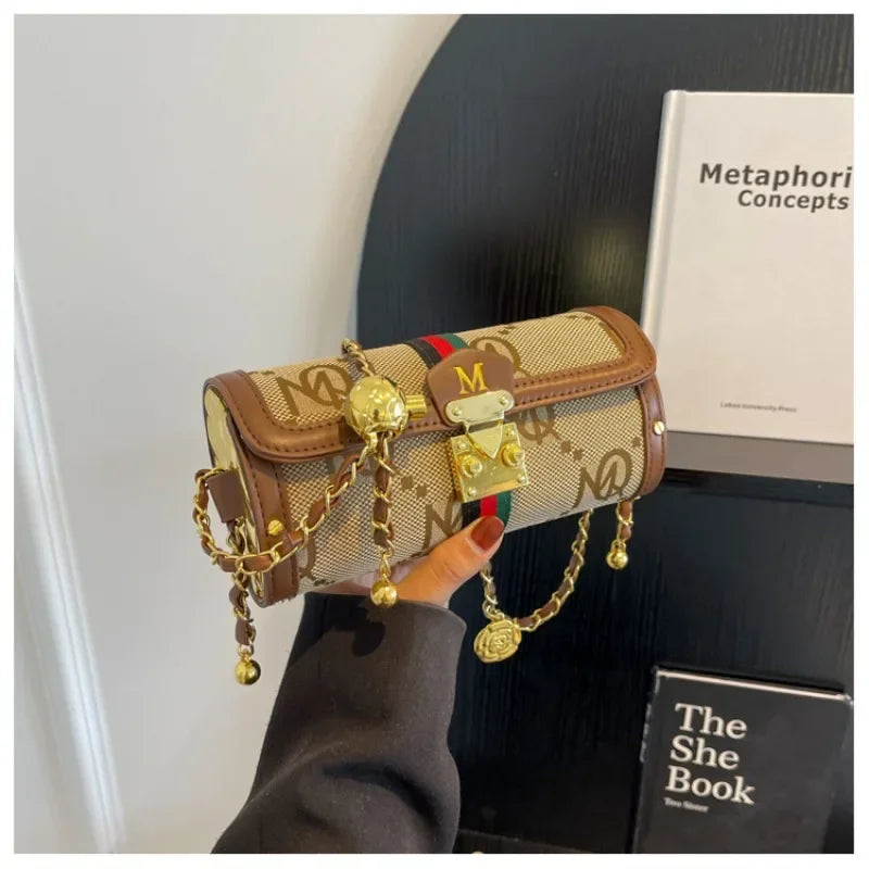 Designer handbag with gold chain and embellishments held by a hand against a blurred background.