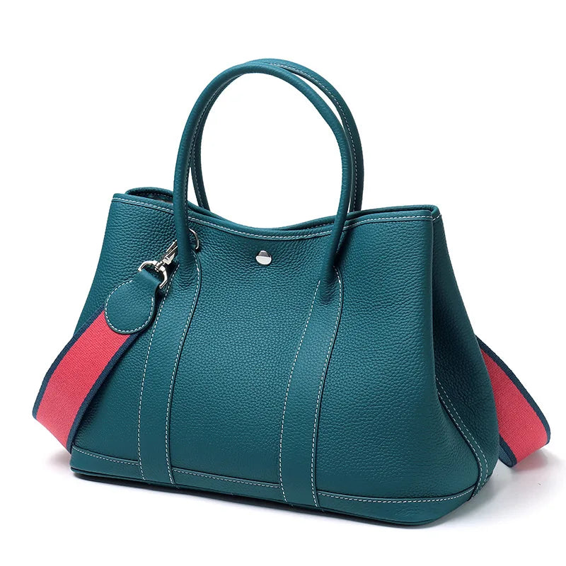 Teal handbag with red interior on a white background