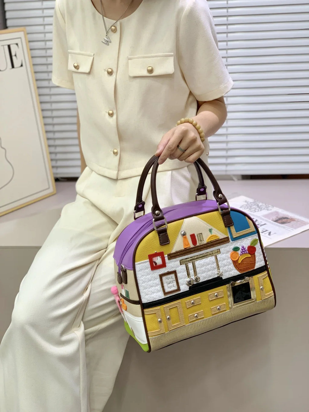 Person holding a colorful handbag with a building design in an indoor setting