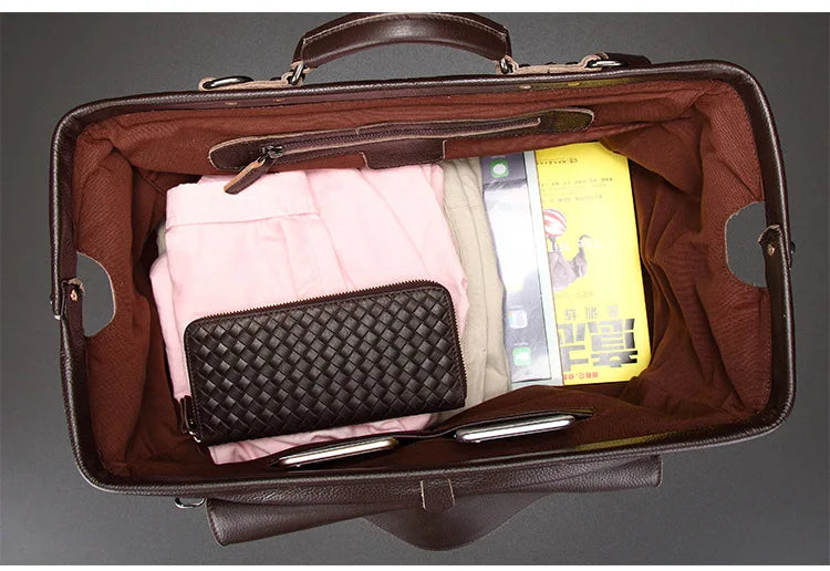 Open brown leather briefcase with pink shirt, black wallet, and yellow book inside.