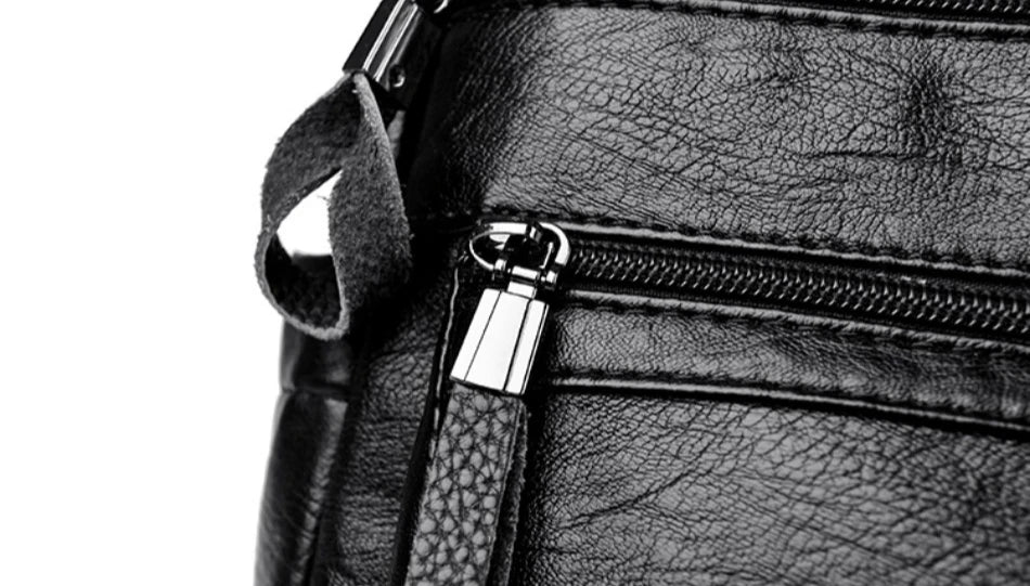 Close-up of a black leather bag with a zipper on a white background